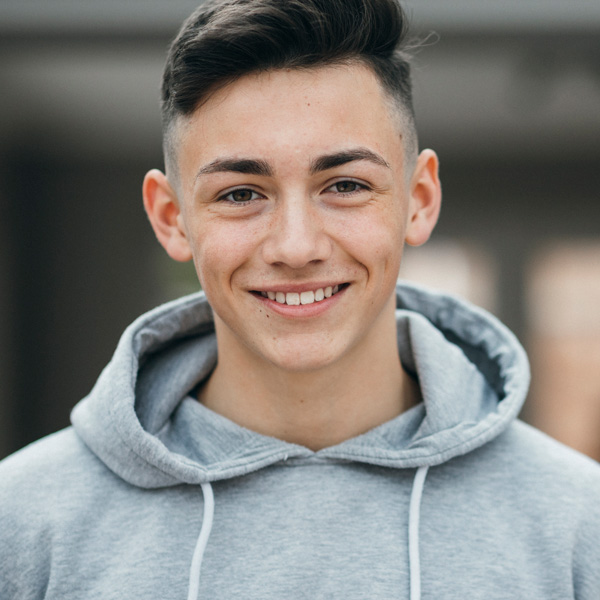 young man in gray hoodie smiling